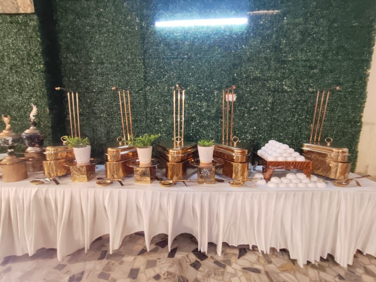Buffet table laid out with covered chafing dishes, serving spoons and stacked bowls
