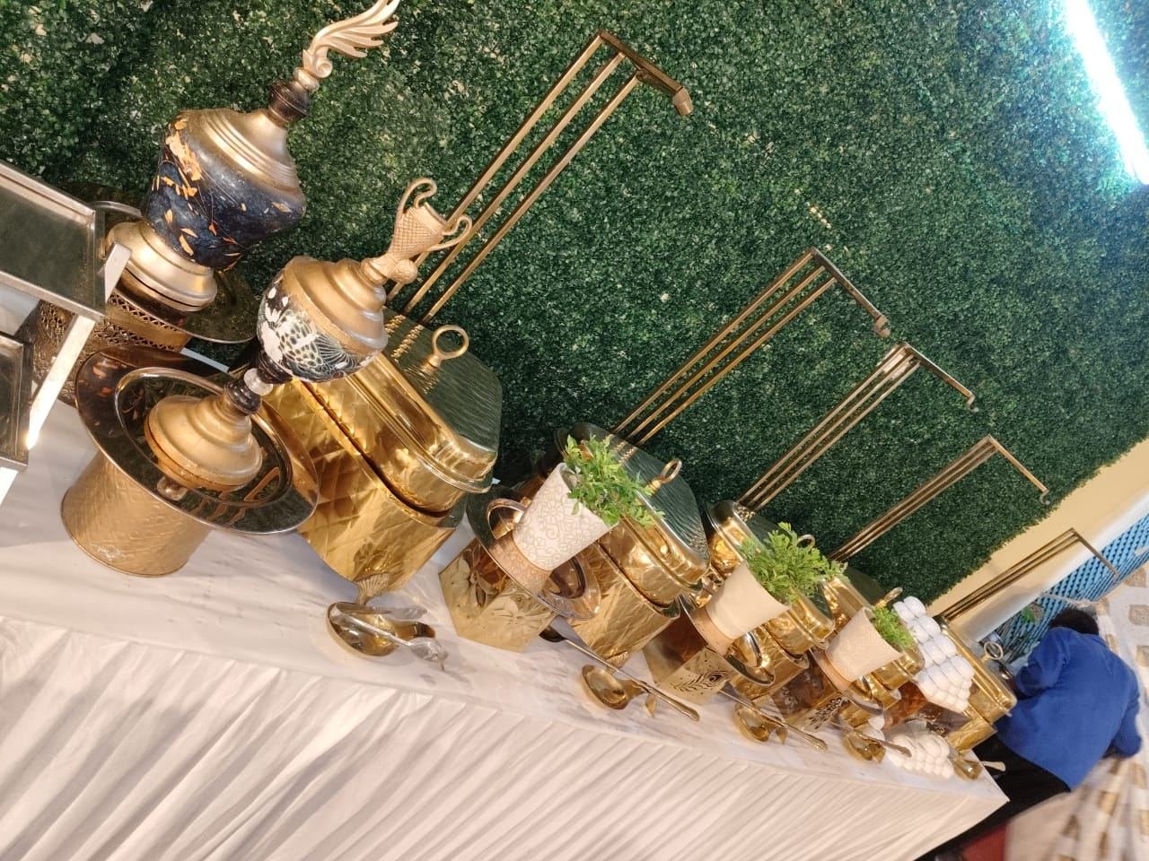 Gold chafing dishes and brass urns lined along a skirted buffet table