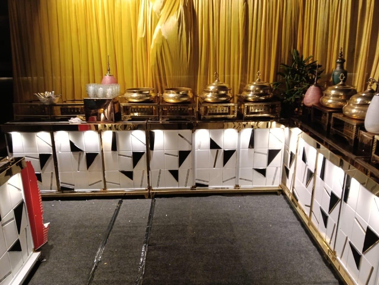 L-shaped buffet counter with backlit panels and brass serving vessels